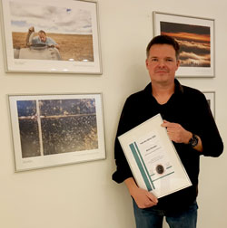 Boris Rössler mit Urkunde neben seinem Foto. © Foto: Diether von Goddenthow