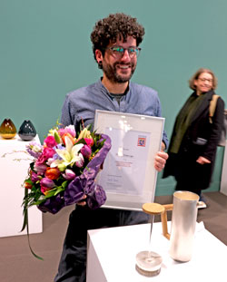 Philipp Gröninger vor seiner handgeschmiedeten silbernen Kaffeepresse mit dem hölzernen Griff, für die er mit dem 2. Preis des 72. Hessischen Staatspreises für das Kunsthandwerk  ausgezeichnet wurde. © Foto: Diether von Goddenthow